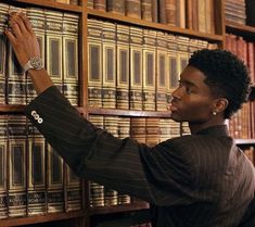 a woman is looking at books on a shelf in a library and she has her hand on the bookcase