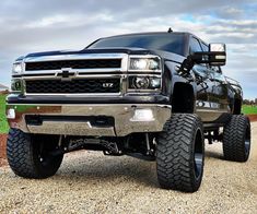 a large black truck parked on top of a gravel road