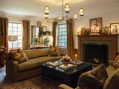 a living room filled with furniture and a fire place under a chandelier in front of a fireplace