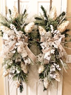 two wreaths with bows and pine cones are hanging on the front door for christmas