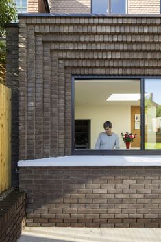 a man standing in the window of a brick house