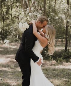 a bride and groom kissing in the woods