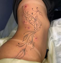 a woman laying in bed with a tattoo on her lower back and bottom part of her stomach