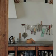 a kitchen counter with pots, pans and utensils hanging on the wall