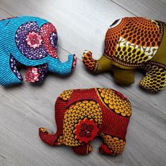 three colorfully painted elephants sitting on top of a wooden floor