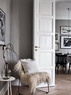 a white door is open to a dining room with pictures on the wall and chairs