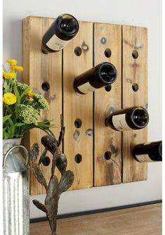 a wooden wine rack with several bottles on it and flowers in the vase next to it