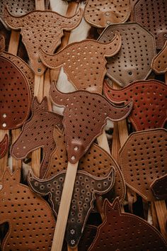 a bunch of brown and black animal shaped cookies on wooden sticks with holes in them