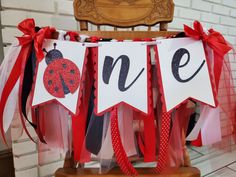 a ladybug birthday banner on a chair with red and black ribbon around it