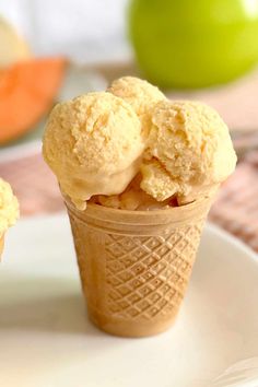 three scoops of ice cream on a white plate with an apple in the background