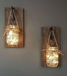 two mason jar lights are hanging on the wall next to each other with string wrapped around them