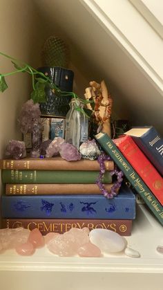 a stack of books sitting on top of a white shelf next to a vase filled with flowers