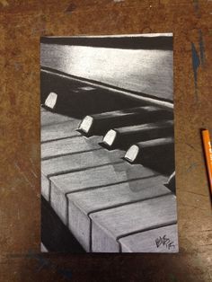 a pencil drawing of a piano keyboard on a wooden table next to a pair of scissors