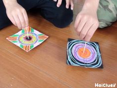 two people are sitting on the floor and one is spinning a pinwheel with sticks