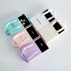 four different colored boxes with bows and jewelry on them, one has a necklace in it