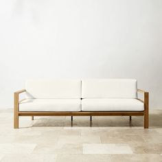 a white couch sitting on top of a tile floor next to a wall with a wooden frame