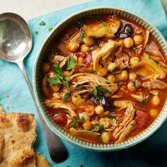 a bowl filled with soup next to some bread on top of a blue napkin and spoon