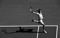 black and white photograph of a tennis player on the court with his racket raised