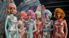 several barbie dolls standing next to each other