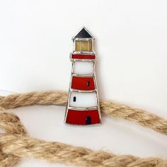 a red and white lighthouse pin sitting on top of a rope