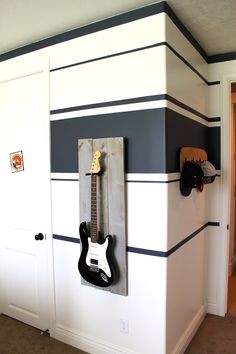 an electric guitar mounted to the side of a white cabinet in a room with carpeted flooring