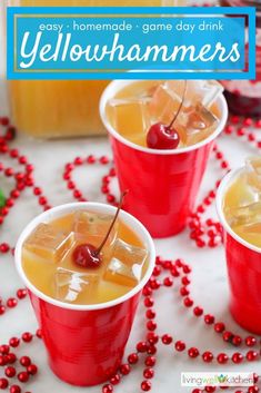 three red cups filled with drinks on top of a white table covered in christmas decorations