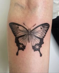 a black and white butterfly tattoo on the left arm, with stars all over it