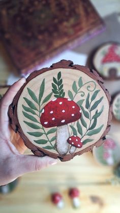 a hand holding a piece of wood with a mushroom on it and leaves around it