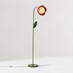 a red flower lamp sitting on top of a green stand next to a white wall