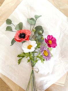 a bunch of flowers sitting on top of a piece of white paper with green leaves