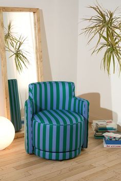 a blue and green striped chair sitting on top of a hard wood floor next to a mirror