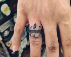 a person's hand with a small tattoo on it and mountains in the background