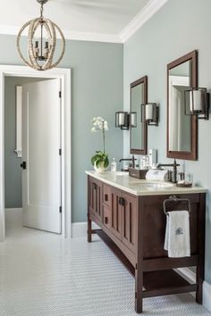 a bathroom with two sinks, mirrors and a chandelier hanging from the ceiling