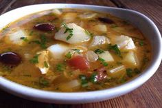 a white bowl filled with soup on top of a wooden table