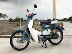 a motor scooter parked in front of a fence