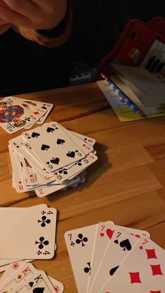 several playing cards on a wooden table with one person reaching for the card in front of them