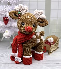 a knitted reindeer sitting next to a christmas tree