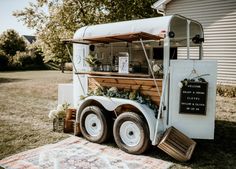 a food truck parked in the grass near a building with a sign on it's side