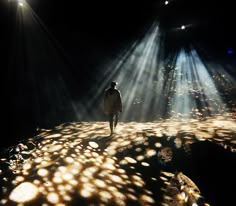 a person standing on top of a rock covered in sunlight beams and rocks with lights coming from them