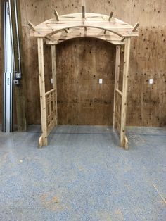 a wooden gazebo sitting on top of a blue floor next to a wall covered in wood planks