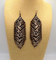 two black and white beaded earrings are on a mannequin headpieces