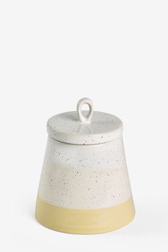 a white and yellow ceramic container with a handle on the top, sitting against a white background