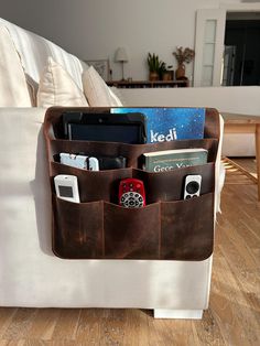 a white couch with some books and electronics in its pocket on it's back