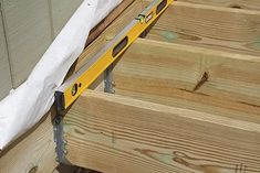 a wooden deck being constructed with a tape measure on the bottom and yellow handrails