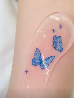 two blue butterflies sitting on the side of a woman's thigh with stars around it