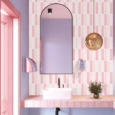 a bathroom with pink and white tiles on the wall, sink and mirror above it