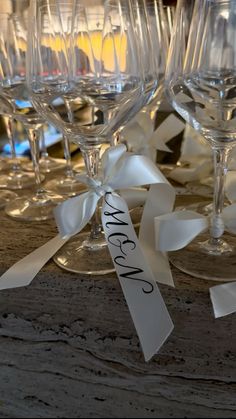 several wine glasses are lined up on a table with ribbon around the stems and name tags