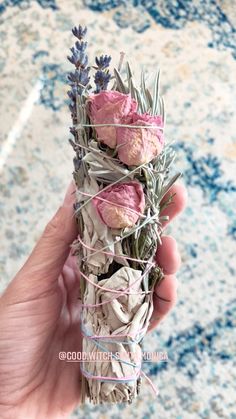 a person holding up a bundle of dried flowers and lavender buds with twine around it