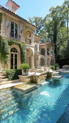 an outdoor swimming pool in front of a large house with steps leading up to it