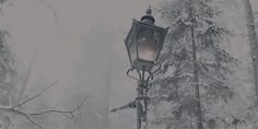 an old fashioned street light in the middle of a snow covered forest with tall trees